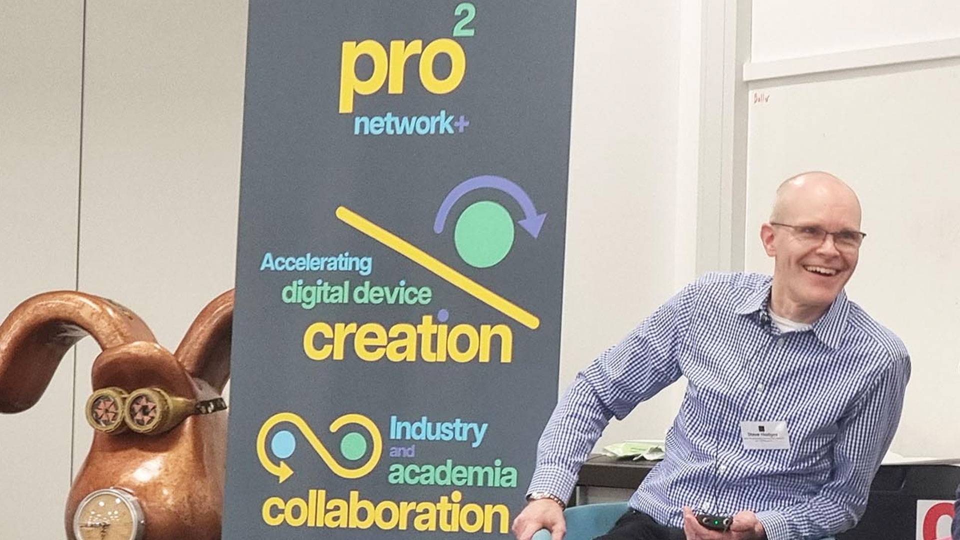 Photo of Steve Hodges speaking at the prosquared launch event with a prosquared poster to the left and a statue of Gromit (from Wallace and Gromit)