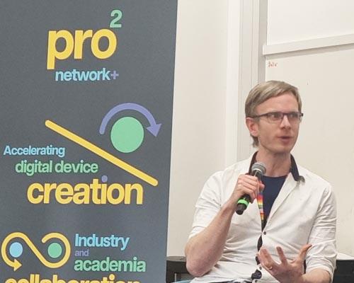Photo of Chris Snider speaking at the prosquared launch event with a prosquared poster to the left