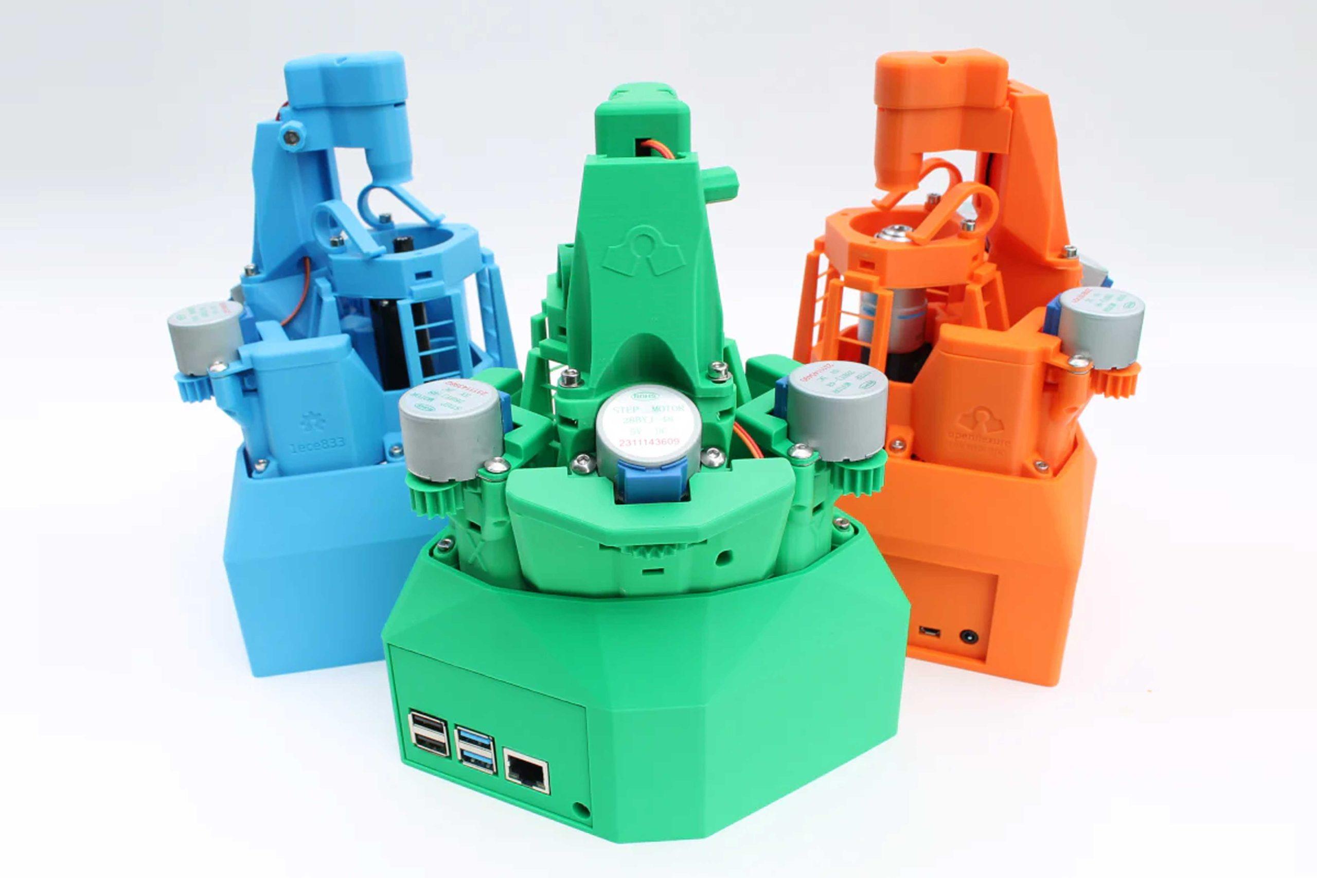 A photo of three OpenFlexure microscopes which have been 3D printed in bright colours against a white background.