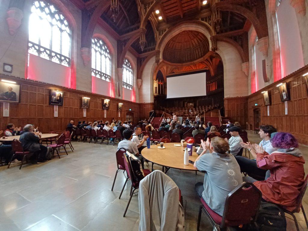 Pre-CHI attendees applaud a speaker in the great hall at the University of Bristol.